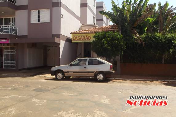 O automóvel encontra-se estacionado em frente a porta de um estabelecimento comercial