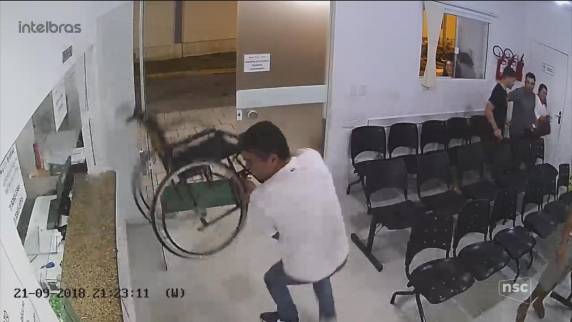 Ele estava há menos de 10 minutos no local quando cometeu agressão. PM faz buscas por ele e filho, que jogou fileira de 

cadeiras no vidro